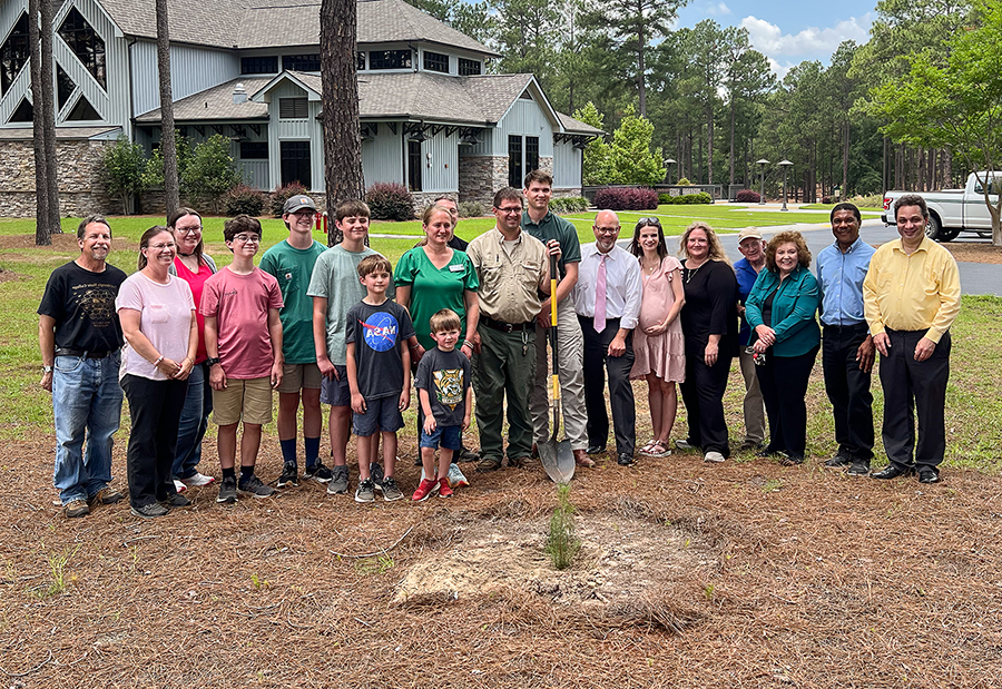 Group stands with newly-planted moon tree